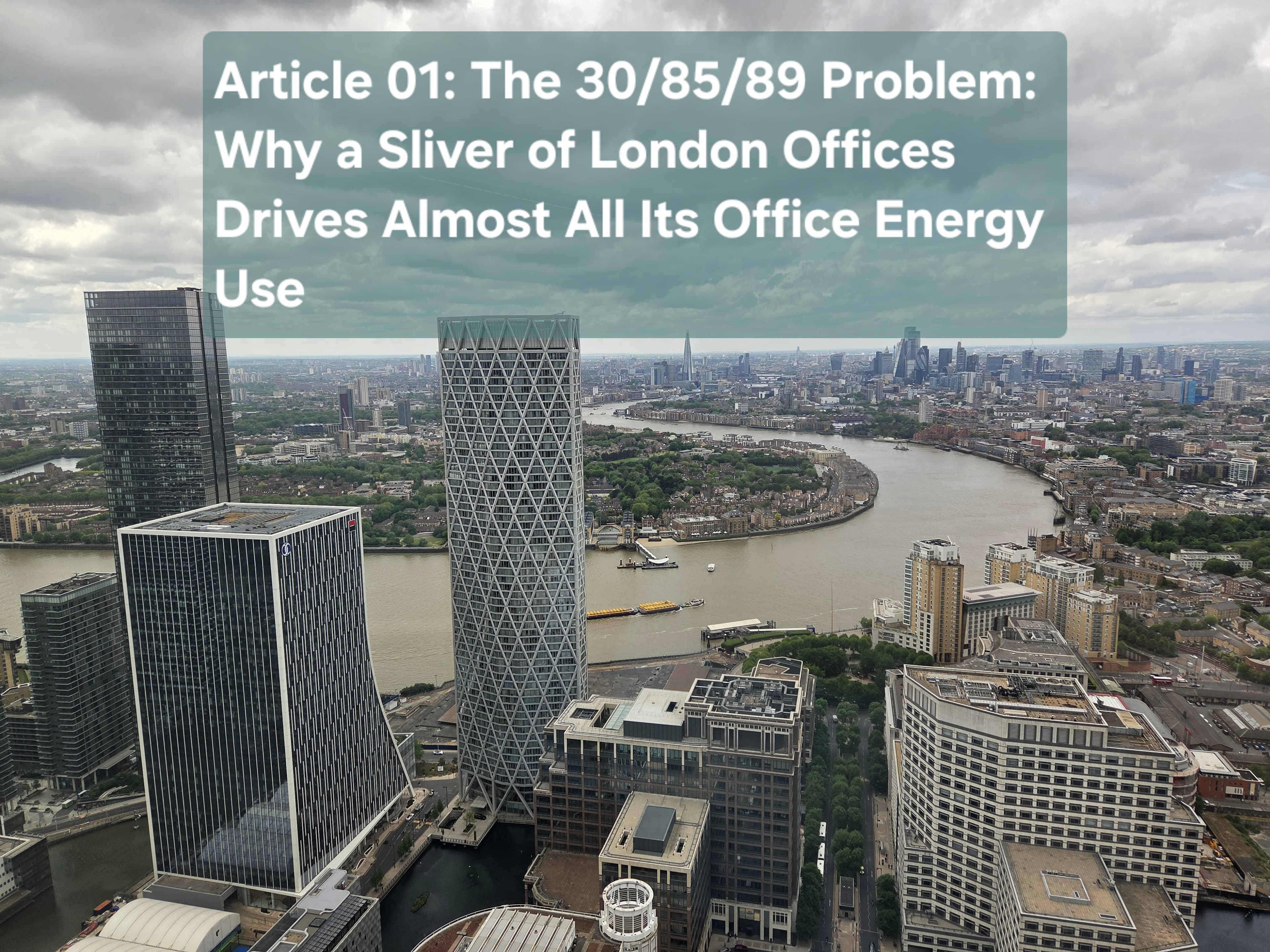 Aerial view of Canary Wharf office towers beside the River Thames under a cloudy sky, the title card for Article 01 on how a small share of large London offices drives almost all office energy use.